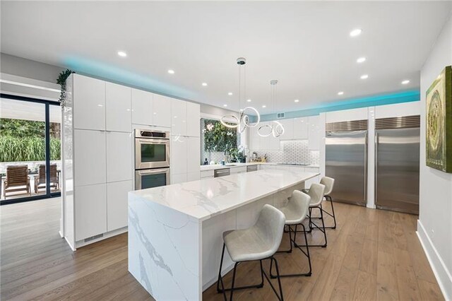 kitchen featuring white cabinetry, a center island, pendant lighting, and appliances with stainless steel finishes