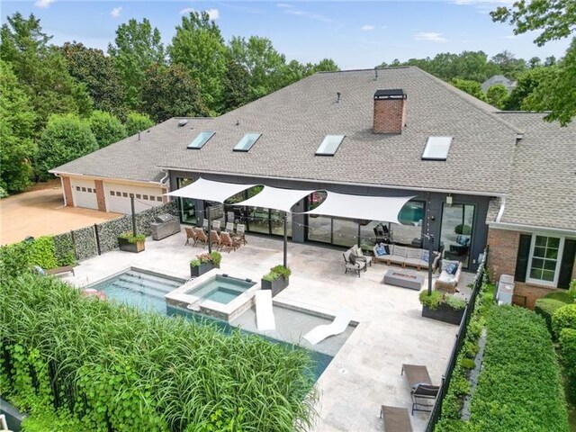 rear view of property featuring outdoor lounge area, a pool with hot tub, and a patio area