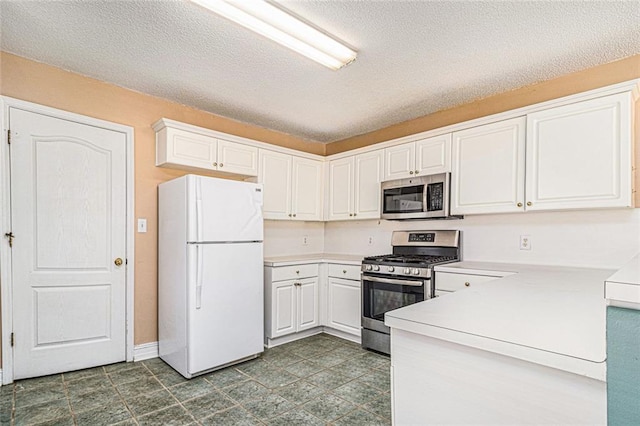 kitchen with a textured ceiling, baseboards, white cabinets, light countertops, and appliances with stainless steel finishes