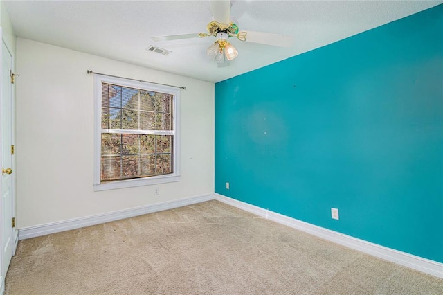 spare room featuring a ceiling fan, light colored carpet, visible vents, and baseboards