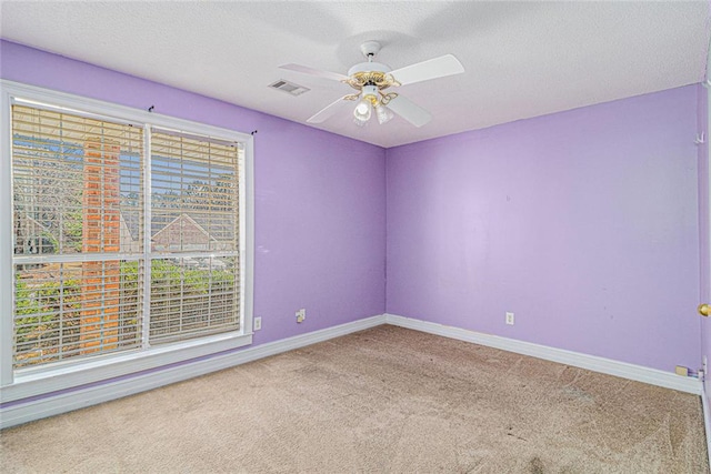 spare room featuring visible vents, baseboards, a ceiling fan, a textured ceiling, and carpet flooring