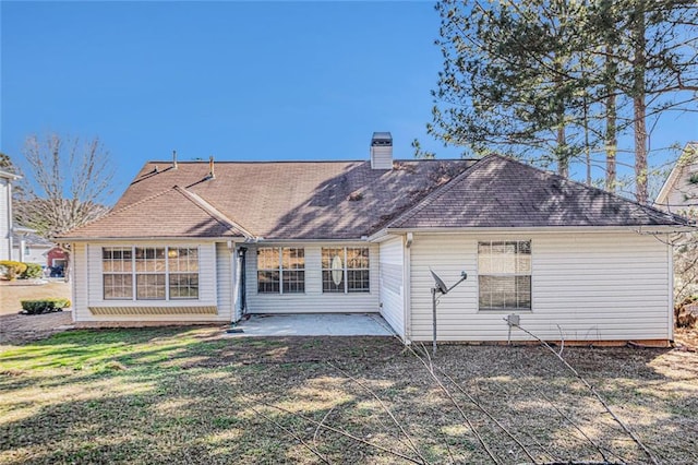 back of house with a yard, a chimney, a patio area, and roof with shingles