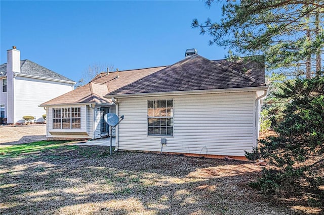 back of property with a patio and roof with shingles