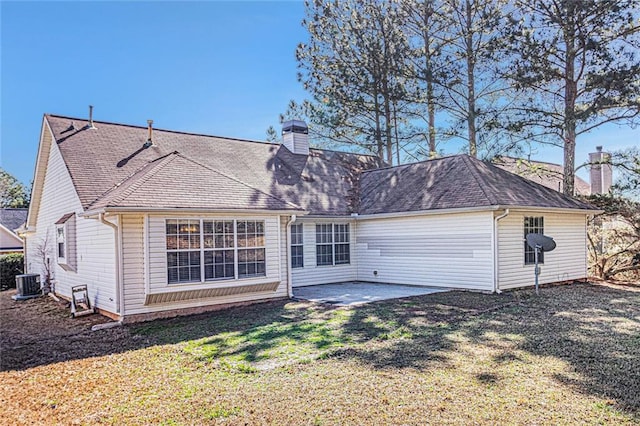 back of house with a lawn, a chimney, roof with shingles, cooling unit, and a patio area