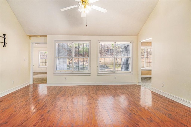 spare room with ceiling fan, vaulted ceiling, baseboards, and wood finished floors