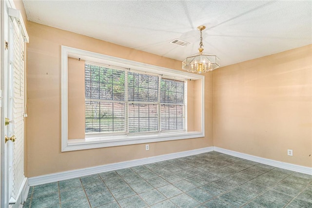 spare room featuring baseboards, a textured ceiling, visible vents, and an inviting chandelier