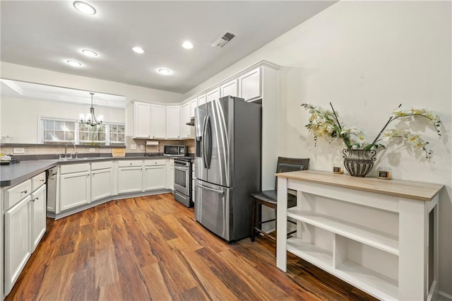 kitchen featuring pendant lighting, sink, dark hardwood / wood-style floors, appliances with stainless steel finishes, and white cabinetry