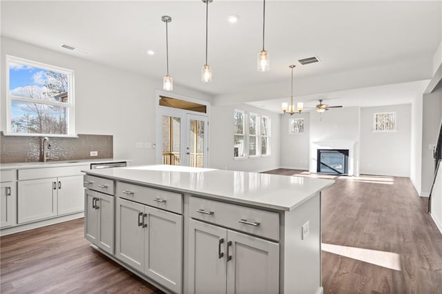 kitchen featuring tasteful backsplash, gray cabinetry, sink, a kitchen island, and pendant lighting