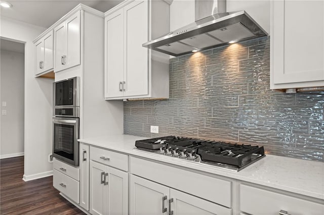 kitchen with wall chimney exhaust hood, white cabinetry, stainless steel appliances, backsplash, and dark hardwood / wood-style floors