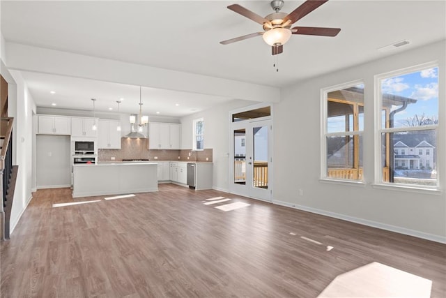 unfurnished living room with sink, light hardwood / wood-style floors, and ceiling fan