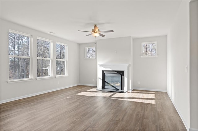 unfurnished living room featuring wood-type flooring, plenty of natural light, and ceiling fan