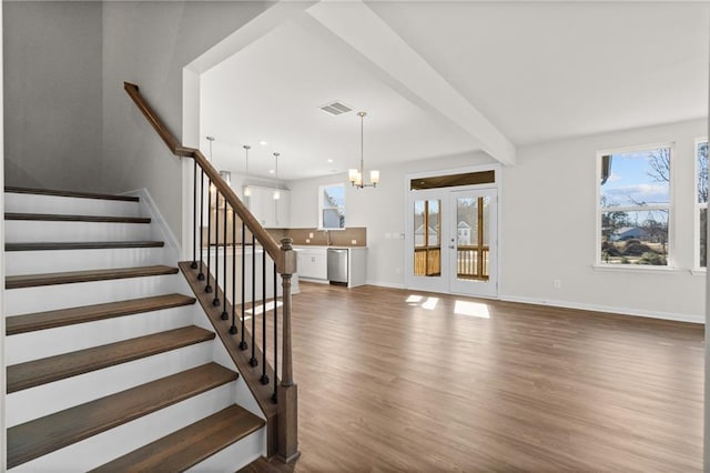 stairs with a notable chandelier, hardwood / wood-style flooring, french doors, and beam ceiling