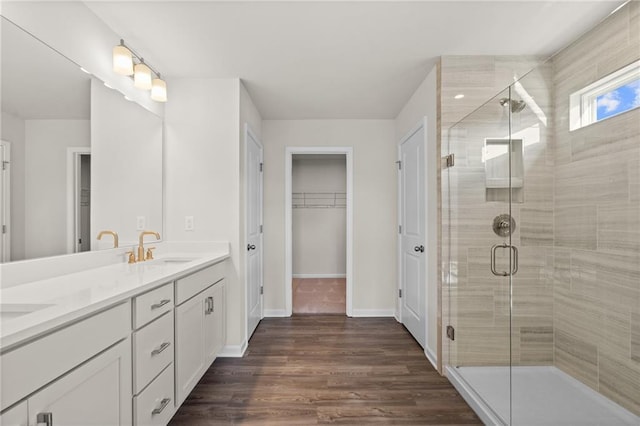 bathroom with a shower with shower door, hardwood / wood-style floors, and vanity