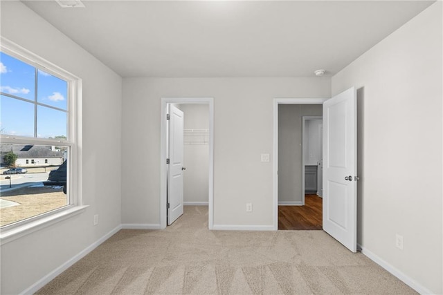 unfurnished bedroom featuring light colored carpet, a closet, and a walk in closet