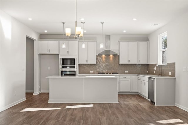 kitchen with white cabinets, decorative light fixtures, a center island, and wall chimney exhaust hood