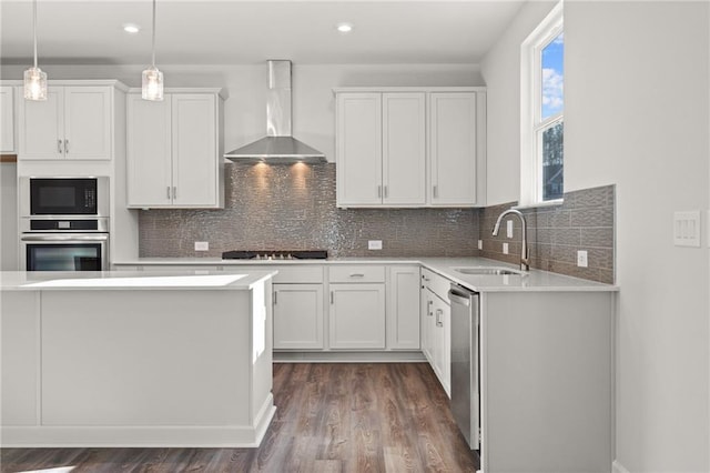 kitchen with sink, white cabinetry, hanging light fixtures, and wall chimney exhaust hood