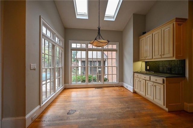 unfurnished dining area featuring light wood-type flooring and vaulted ceiling with skylight