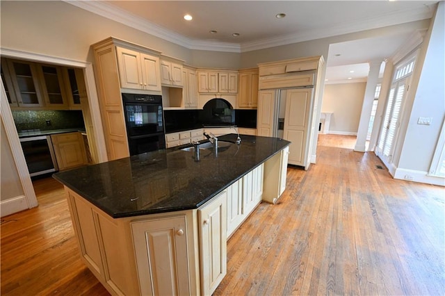 kitchen with backsplash, a kitchen island with sink, crown molding, light hardwood / wood-style flooring, and double oven