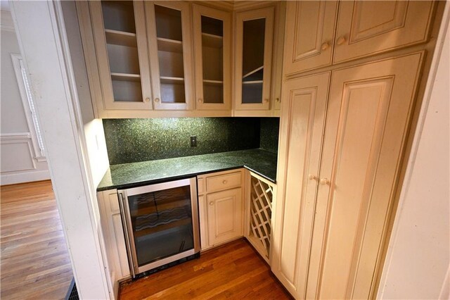 bar with wine cooler and dark wood-type flooring