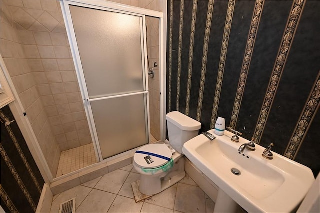 bathroom with tile patterned floors, toilet, a shower with shower door, and sink