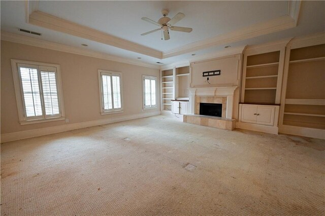 unfurnished living room featuring a tray ceiling, a wealth of natural light, and ornamental molding