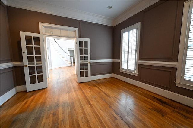 empty room featuring french doors, wood-type flooring, and ornamental molding