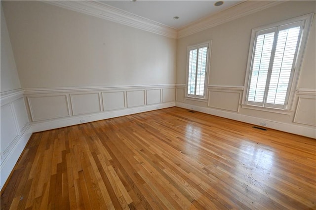spare room with crown molding, plenty of natural light, and light hardwood / wood-style floors