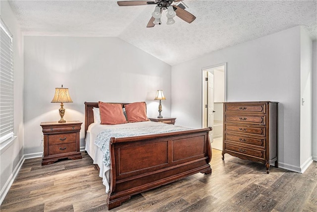 bedroom with vaulted ceiling, dark hardwood / wood-style floors, ceiling fan, and a textured ceiling