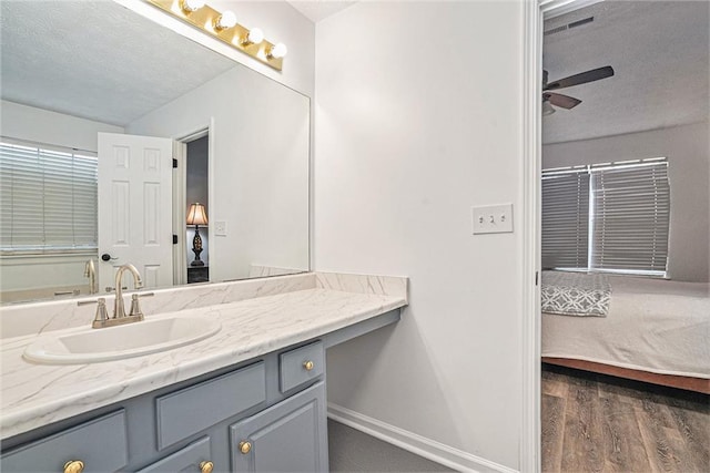 bathroom featuring ceiling fan, vanity, hardwood / wood-style floors, and a textured ceiling