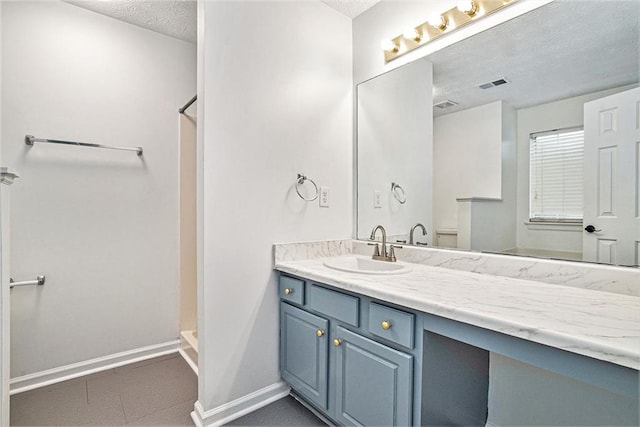 bathroom featuring vanity, a textured ceiling, and a shower