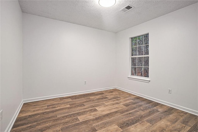 empty room with a textured ceiling and dark hardwood / wood-style flooring