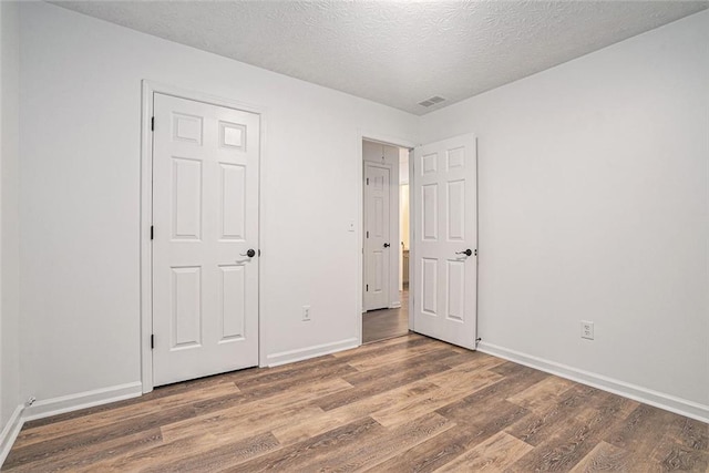 unfurnished bedroom featuring dark hardwood / wood-style flooring and a textured ceiling