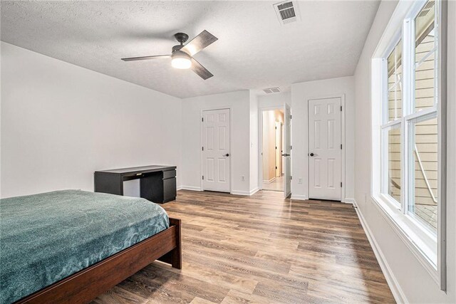 bedroom featuring ceiling fan, hardwood / wood-style flooring, and a textured ceiling