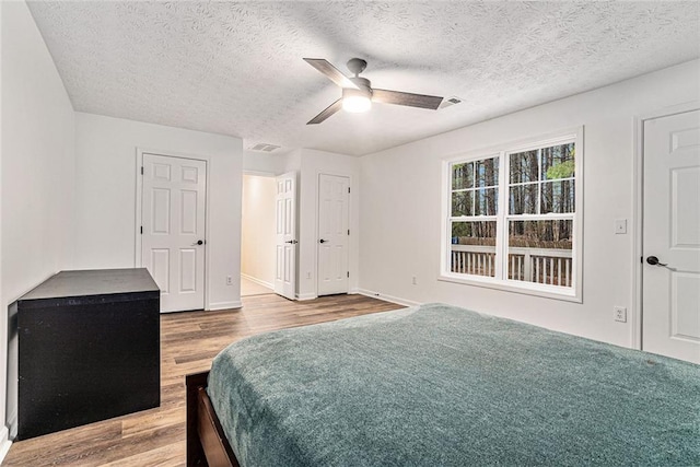 bedroom with a textured ceiling, ceiling fan, and light hardwood / wood-style flooring