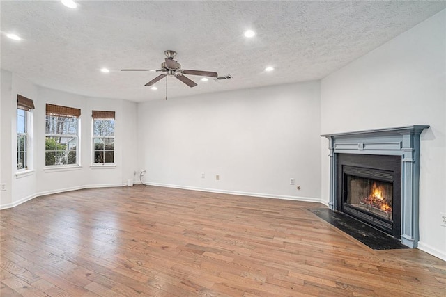 unfurnished living room with a textured ceiling, light hardwood / wood-style floors, and ceiling fan