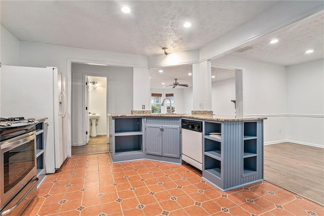 kitchen with dishwasher, sink, kitchen peninsula, stainless steel range oven, and a textured ceiling