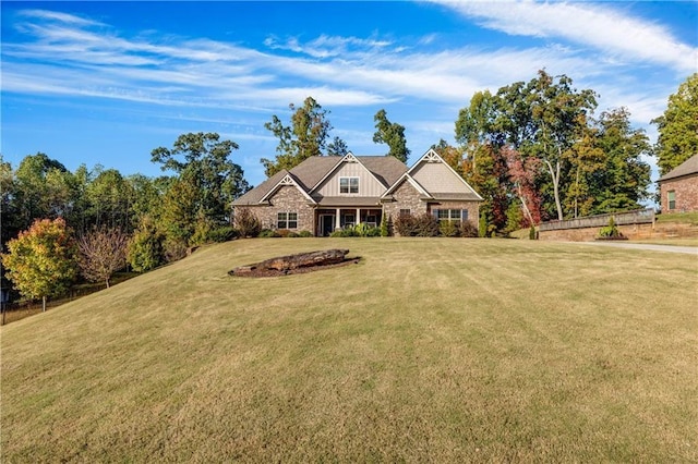 view of front of house featuring board and batten siding, stone siding, and a front lawn