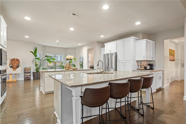 kitchen with visible vents, a large island, appliances with stainless steel finishes, and white cabinetry