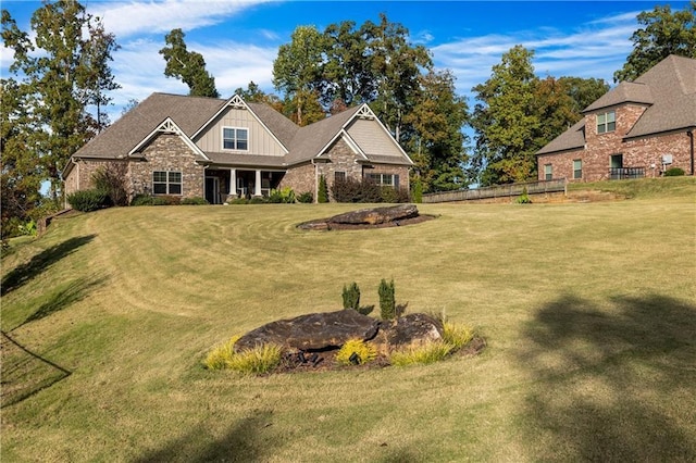 view of front of property with stone siding, fence, a front lawn, and board and batten siding