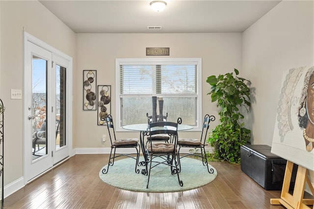 dining space featuring hardwood / wood-style floors, visible vents, and baseboards