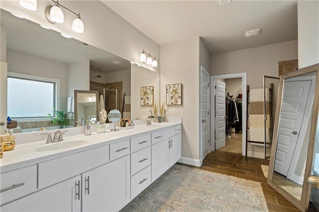 full bathroom with wood finish floors, a sink, a spacious closet, a shower stall, and double vanity