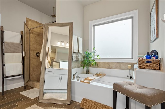 bathroom featuring a bath, a shower stall, vanity, and wood tiled floor