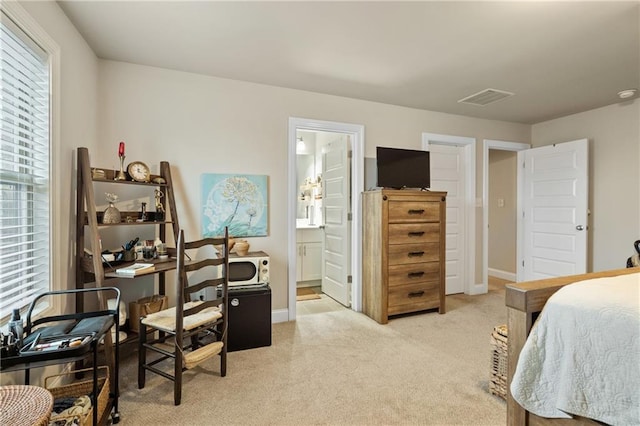 bedroom with light carpet, ensuite bath, visible vents, and baseboards