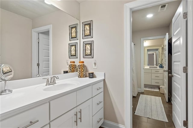 bathroom featuring visible vents, vanity, baseboards, and tile patterned floors