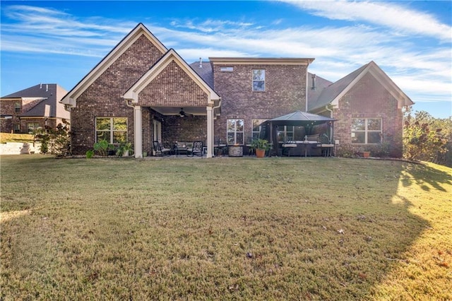 back of house featuring brick siding, a yard, a ceiling fan, and a gazebo