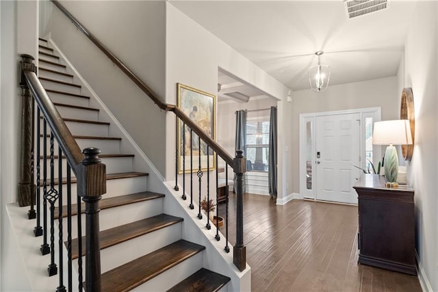 entryway featuring dark wood-style floors, visible vents, an inviting chandelier, baseboards, and stairs