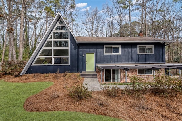 view of front of property with brick siding, board and batten siding, and a front lawn