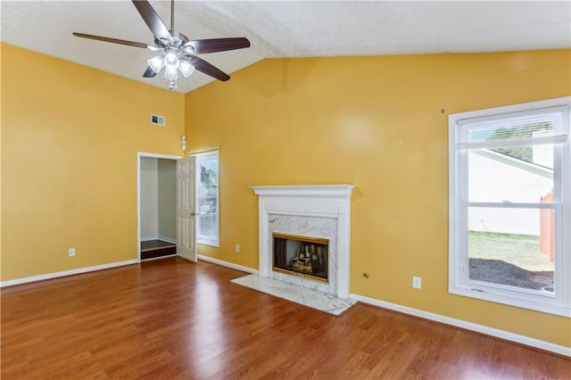 unfurnished living room featuring baseboards, a fireplace, wood finished floors, a ceiling fan, and vaulted ceiling