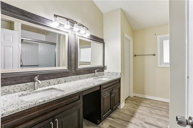 bathroom with double vanity, a sink, baseboards, and wood finished floors