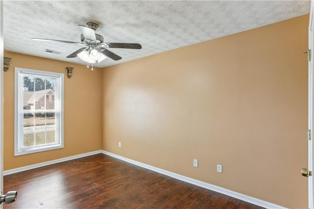 unfurnished room with dark wood-type flooring, baseboards, visible vents, and a ceiling fan